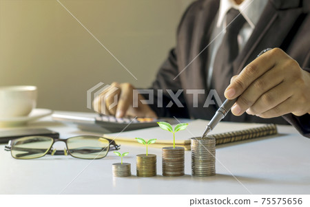 Businessman holding a pen and a tree growing on a coin, planning ideas for investing and growing money. Businessman holding a pen and a tree growing on a coin, planning ideas for investing and growing money. 75575656
