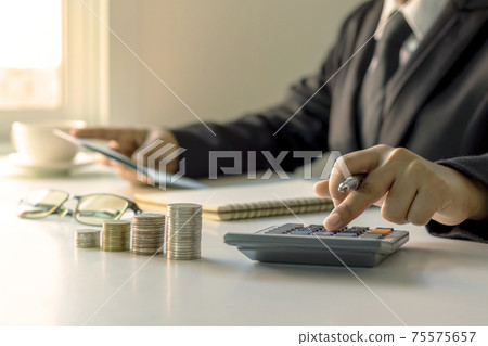 The businessman is holding a pen and pressing to a calculator, ideas for planning for investment and money growth. 75575657