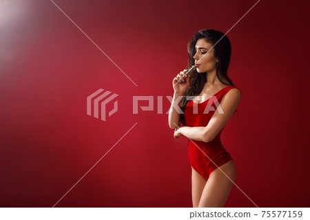 Young sexy woman in red body is vaping. 75577159