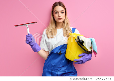 young caucasian female is exhausted of cleaning, holding cleanser things 75577383