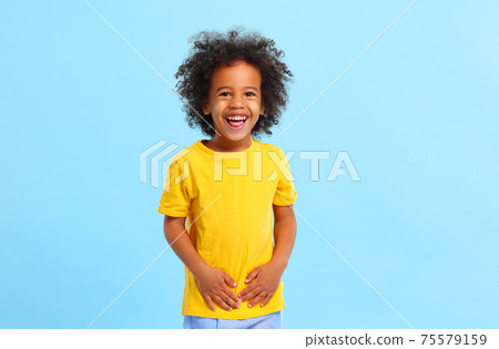Positive African American little boy laughing in blue studio Positive African American little boy laughing in blue studio 75579159