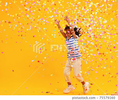 Excited African American kid jumping and catching confetti on birthday in studio Excited African American kid jumping and catching confetti on birthday in studio 75579160