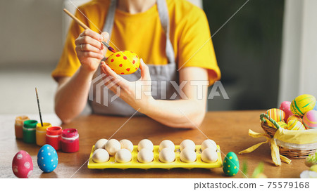 Crop woman painting eggs for Easter celebration 75579168