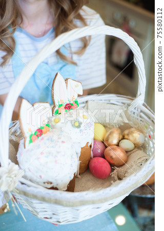 Beautiful mother with a basket of Easter cakes in her hands in the kitchen. Beautiful mother with a basket of Easter cakes in her hands in the kitchen. 75580112