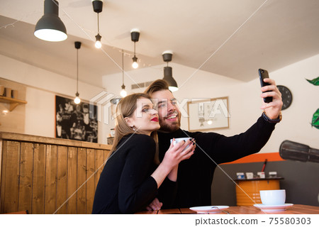 Beautiful Smiling Couple In Cafe Using Phone 75580303