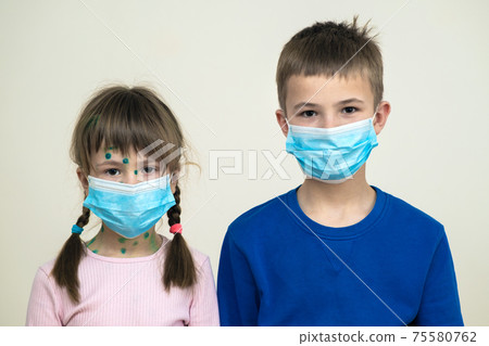 Boy and girl wearing blue protective medical mask ill with chickenpox, measles or rubella virus with rashes on body. Children protection during epidemic of coronovirus. Covid-19 contagion concept. 75580762