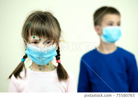 Boy and girl wearing blue protective medical mask ill with chickenpox, measles or rubella virus with rashes on body. Children protection during epidemic of coronovirus. Covid-19 contagion concept. 75580763