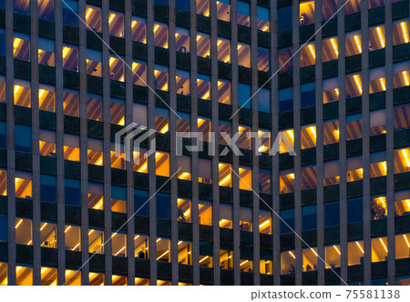 A Modern skyscraper facade silhouette at twilight with lit up windows with people still working 75581138