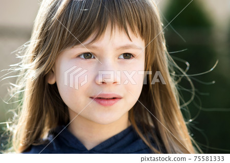 Portrait of pretty child girl with gray eyes and long fair hair outdoors on blurred bright background. Cute female kid on warm summer day outside. Portrait of pretty child girl with gray eyes and long fair hair outdoors on blurred bright background. Cute female kid on warm summer day outside. 75581333