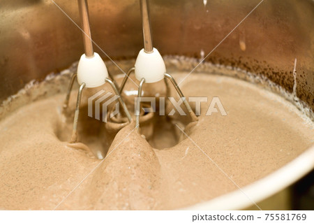 Closeup of electrical blender whipping in bowl chocolate cream for cake, ice cream or dessert. Kitchen bakery equipment, homemade baking. 75581769