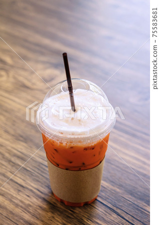 Thai iced tea on wood table in cafe. Thai iced tea on wood table in cafe. 75583681