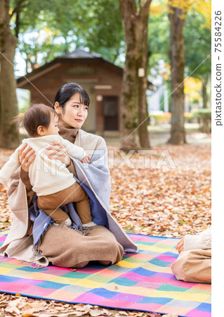 A woman hugging her baby in the park and talking to her mom friend (in trouble) A woman hugging her baby in the park and talking to her mom friend (in trouble) 75584226