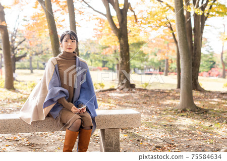 Woman with a smartphone in the autumn park 75584634