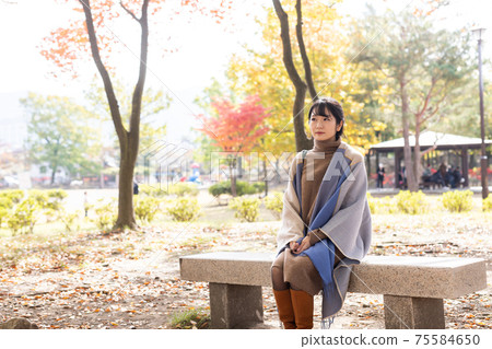 A woman standing in an autumn park 75584650