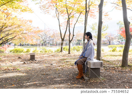 A woman standing in an autumn park 75584652