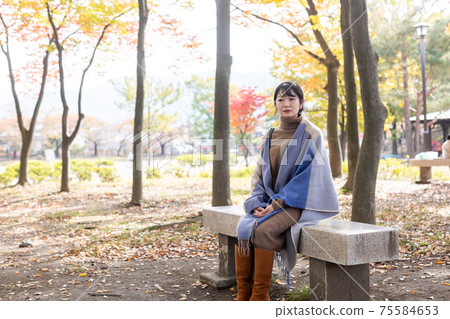 A woman standing in an autumn park 75584653