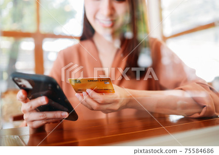 Woman making payment on phone with card Woman making payment on phone with card 75584686