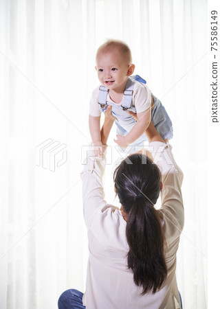Mother lifting little son 75586149