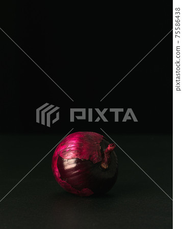 Front view to red onion with husk on black Front view to red onion with husk on black 75586438
