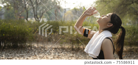 Horizontal photo of fitness woman drinking water from bottle after doing jogging outdoors. Horizontal photo of fitness woman drinking water from bottle after doing jogging outdoors. 75586911