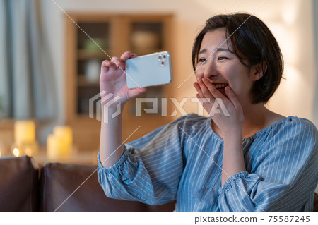 在晚上打視頻通話在她的智能手機上的年輕女子 75587245