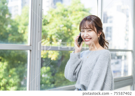 一個女人在窗邊打個電話商業場景 75587402