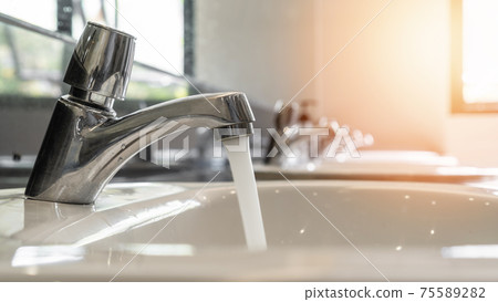 Tap water running wastage from faucet over hand washing sink, ceramic basin in water closet, public wc room or school bathroom for saving ecological and environmental conservation awareness concept Tap water running wastage from faucet over hand washing sink, ceramic basin in water closet, public wc room or school bathroom for saving ecological and environmental conservation awareness concept 75589282