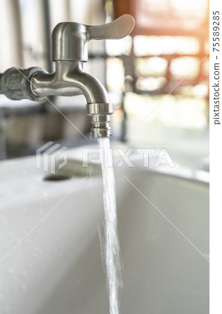 Tap water running wastage from faucet over hand washing sink, ceramic basin in water closet, public wc room or school bathroom for saving ecological and environmental conservation awareness concept Tap water running wastage from faucet over hand washing sink, ceramic basin in water closet, public wc room or school bathroom for saving ecological and environmental conservation awareness concept 75589285