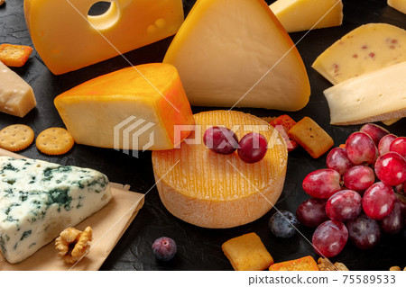 Cheese and grapes on a table, an assortment of various cheeses Cheese and grapes on a table, an assortment of various cheeses 75589533