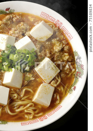 熱麻婆豆腐拉麵和日本胡椒，在黑色背景上拍了很多通用洋蔥（頂視圖） 75589834