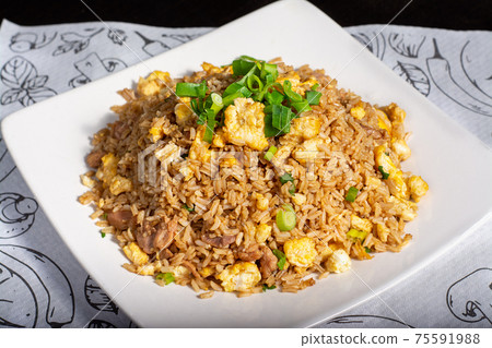 Peruvian traditional food. Rice with meat and vegetable, scramble eggs decorated with onian feather. Arroz chaufa Peruvian traditional food. Rice with meat and vegetable, scramble eggs decorated with onian feather. Arroz chaufa 75591988
