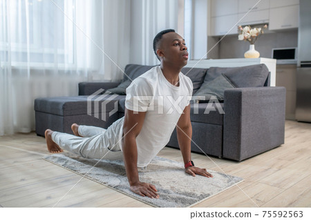 African american guy in white clothes having ahome workout 75592563