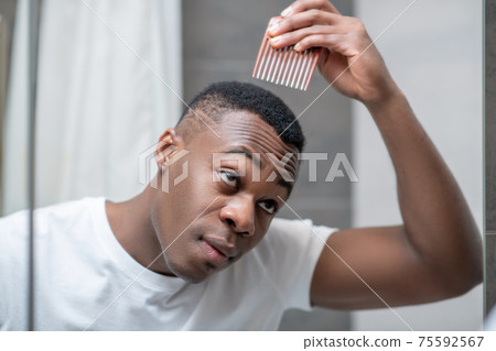 African american guy in white tshirt doing his hair 75592567