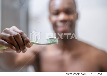 African american short-haired guy looking at himself in the mirror African american short-haired guy looking at himself in the mirror 75592586