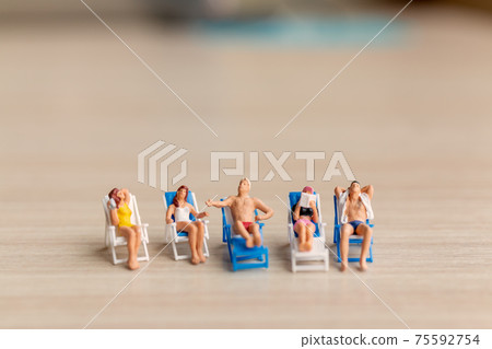 Miniature people sunbathing on The beach 75592754