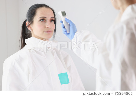 For doctor in protective suit, body temperature is measured with thermometer after work shift For doctor in protective suit, body temperature is measured with thermometer after work shift 75594865