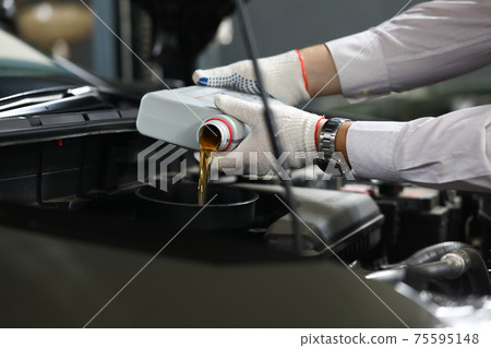 Foreman pours engine oil into engine closeup Foreman pours engine oil into engine closeup 75595148