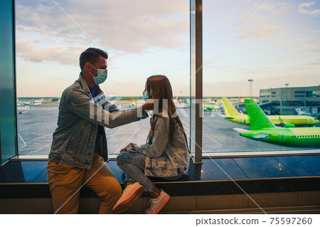 Dad and little girl with medical masks at airport. Protection against Coronavirus and gripp Dad and little girl with medical masks at airport. Protection against Coronavirus and gripp 75597260