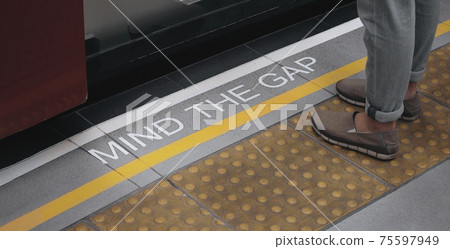 Mind the gap sign. text on train station platform. white text signal on metro or underground floor. Yellow line train station. london england europe old transport platform. Mind the gap for safety. 75597949