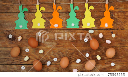 Happy Easter background. Garland of paper rabbits on a wooden background. Happy Easter background. Garland of paper rabbits on a wooden background. 75598235
