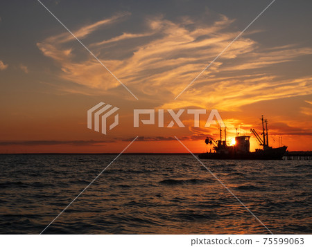 Beautiful orange sunset on sea water. Transport ship on the dock in the evening on seacoast. Shipping logistic by sea. Beautiful orange sunset on sea water. Transport ship on the dock in the evening on seacoast. Shipping logistic by sea. 75599063