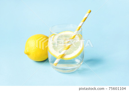 Glass of water with lemon on a blue background. 75601104