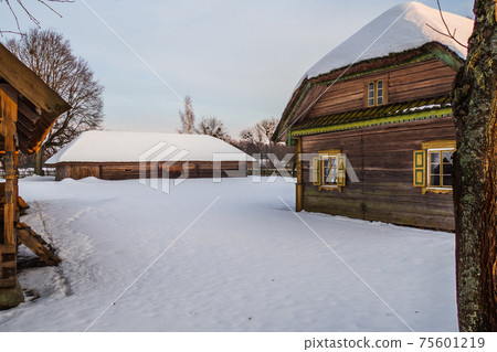 Old Village Wooden Houses and Sheds on a Snowy Slope 75601219
