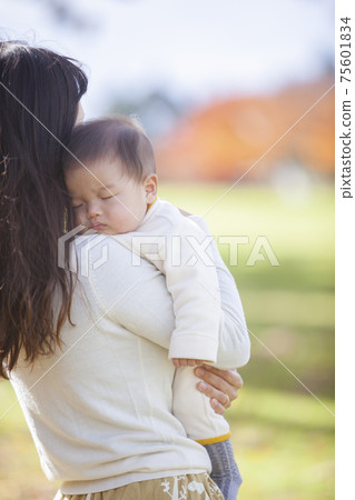 Baby sleeping embraced by mom 75601834