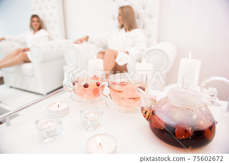Two famale friends in spa have fun, talk drinking fruit tea. 75602672