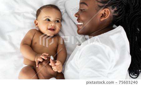 African American mom lying in bed with her cute baby African American mom lying in bed with her cute baby 75603240
