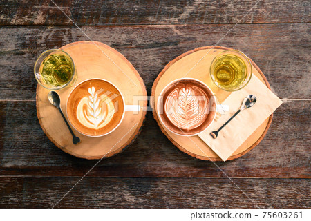 Cup of latte art coffee and chocolate art with hot tea on wooden table, Top view Cup of latte art coffee and chocolate art with hot tea on wooden table, Top view 75603261