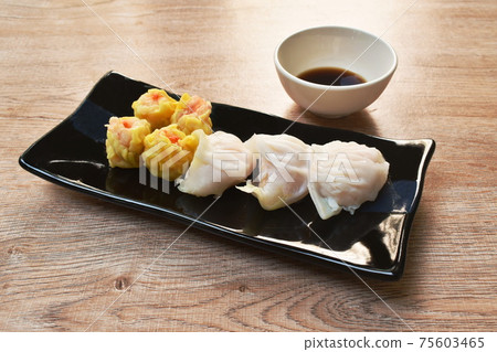 Ha Kao or white and yellow dumpling stuffed shrimp and pork on plate dipping soy sauce Ha Kao or white and yellow dumpling stuffed shrimp and pork on plate dipping soy sauce 75603465