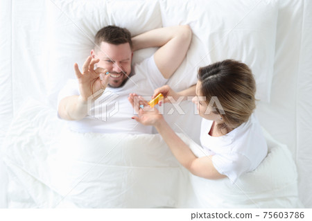 Woman giving man pill in bed top view Woman giving man pill in bed top view 75603786