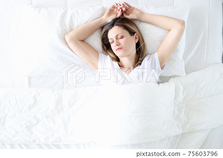 Young woman sleeping in white bed top view 75603796